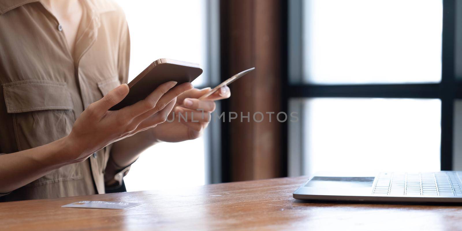 Close up woman paying online by credit card, using smartphone, entering information, young female holding phone, browsing banking service, checking balance, shopping, ordering in internet by wichayada