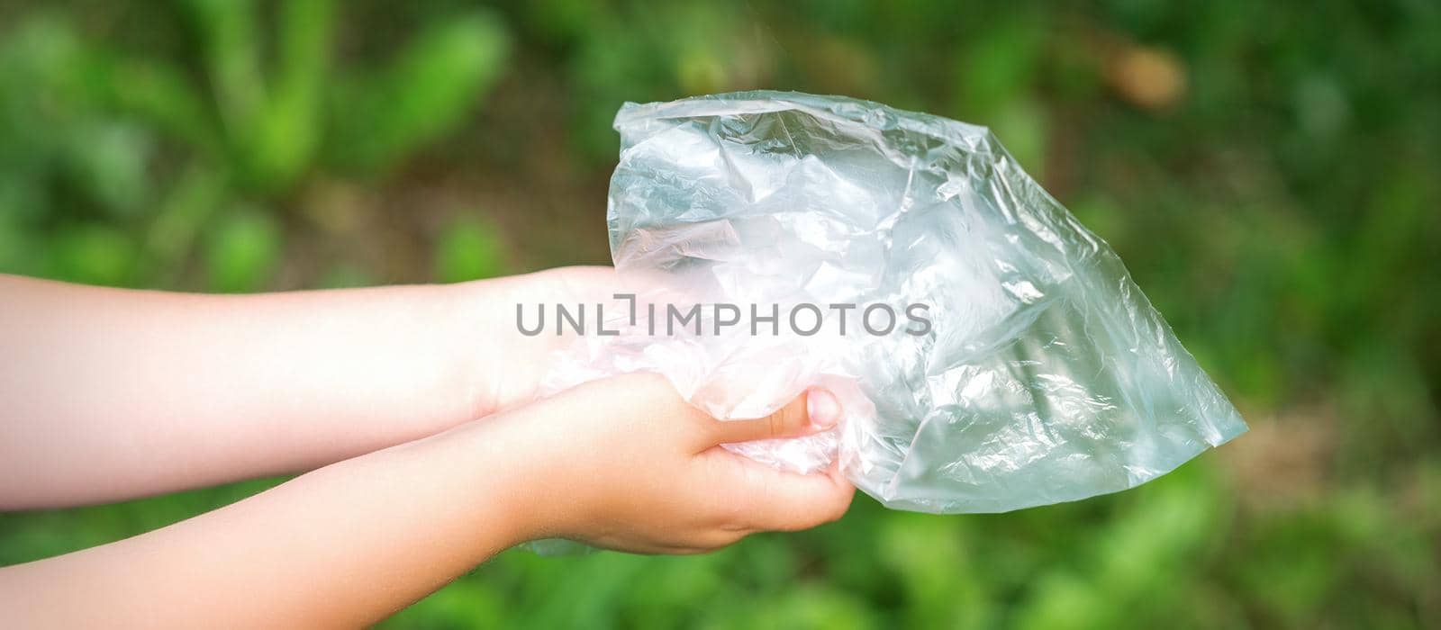 Used empty plastic bag in hands of a little girl while cleaning the park from debris