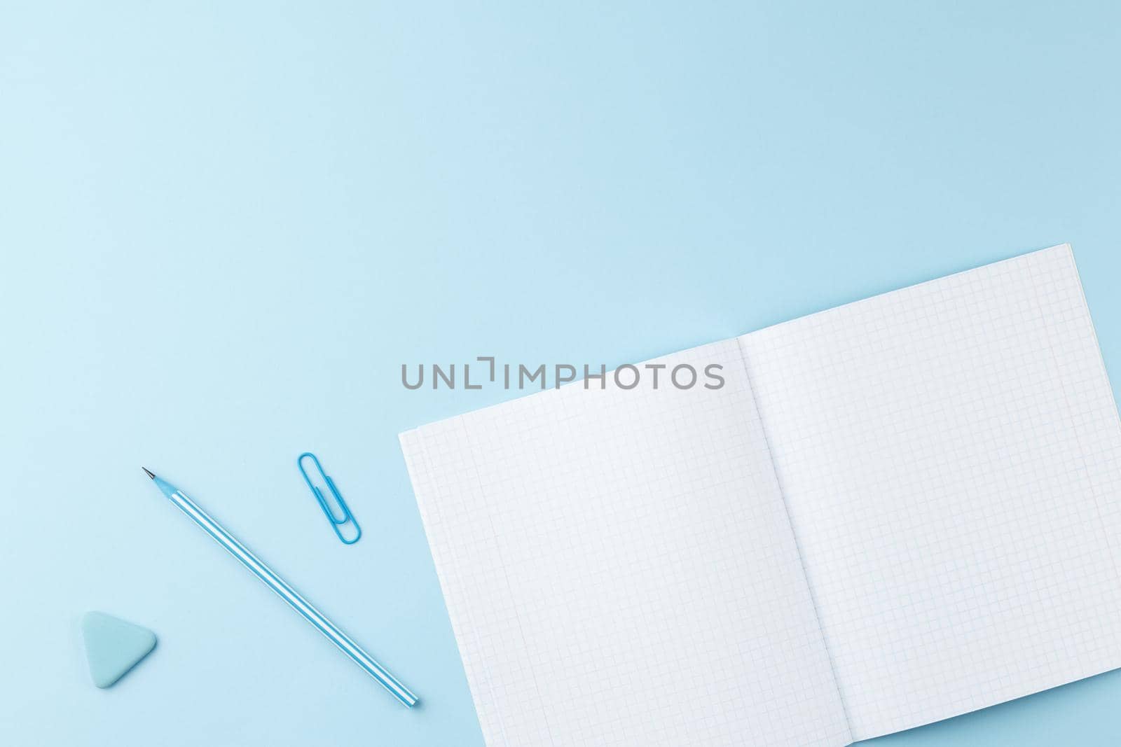 Open school notebook with school supplies on a blue background. Top view. Study desk flat lay. Concept back to school.