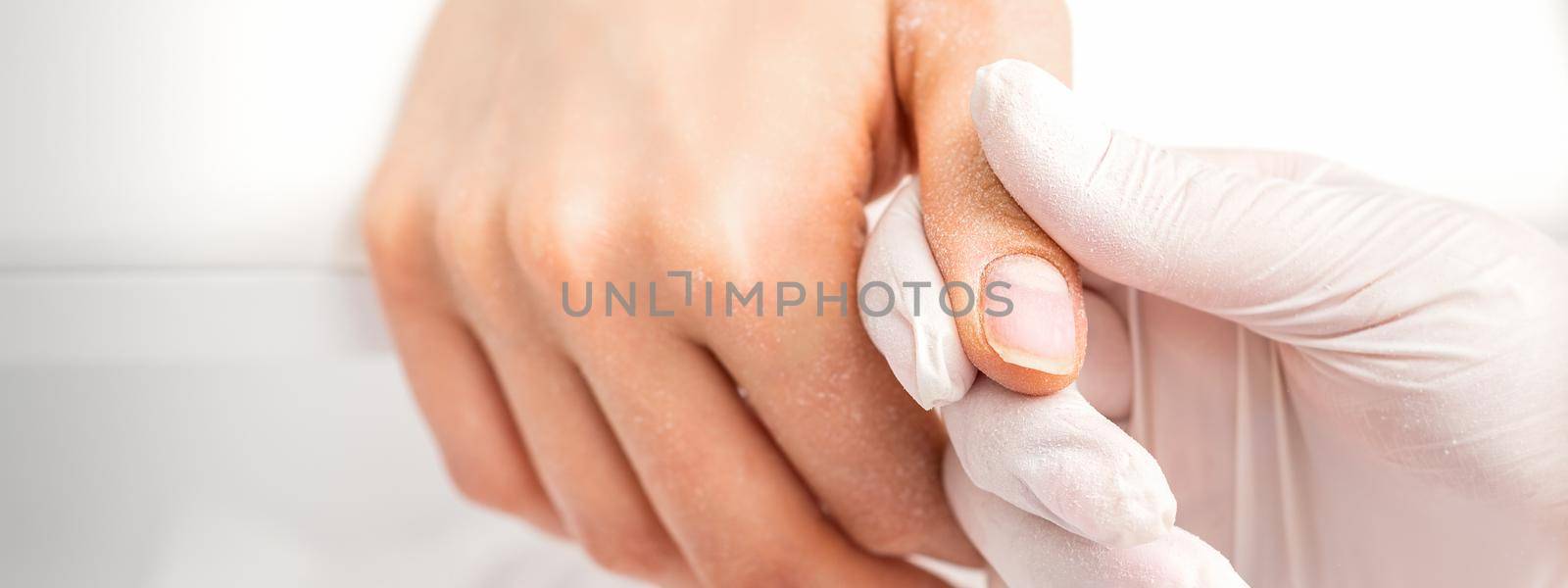 The manicurist holds the woman's thumb during a manicure procedure in the nail salon