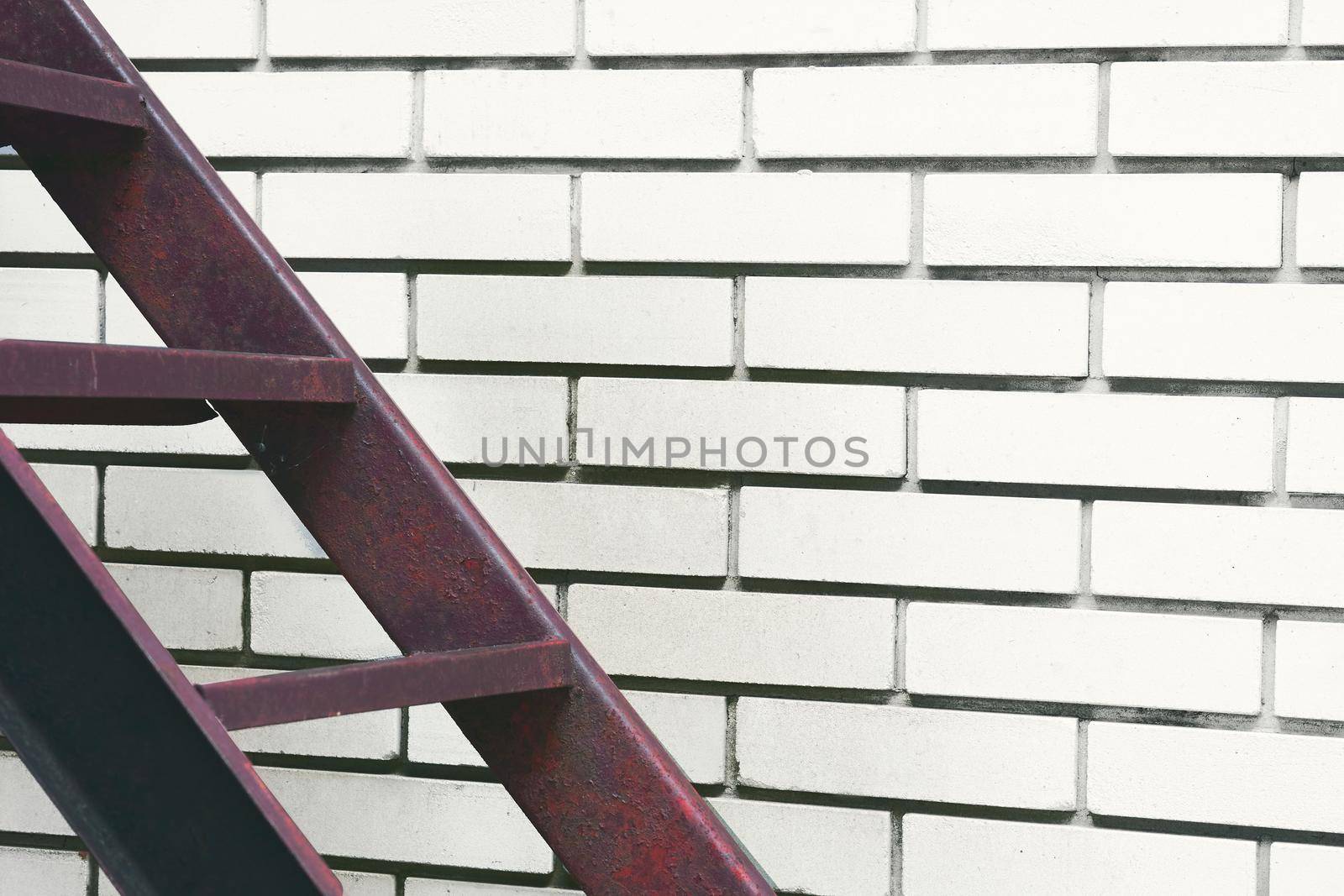 Part of the stairs red metal ladder leading up against of a white brick wall by jovani68