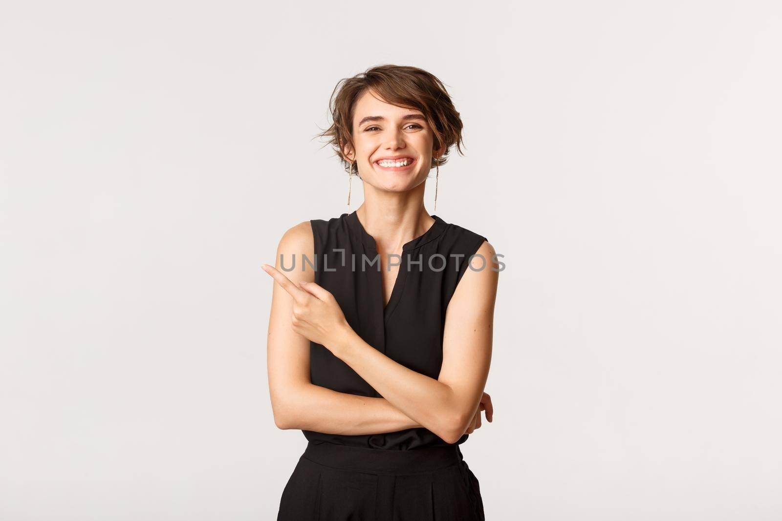 Image of cheerful pretty woman laughing and pointing finger upper left corner, showing logo, white background.