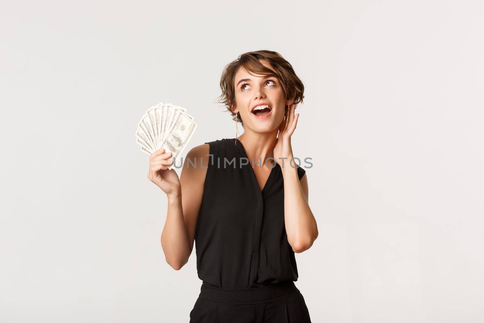 Gorgeous rich girl showing money and looking sassy, standing over white background by Benzoix