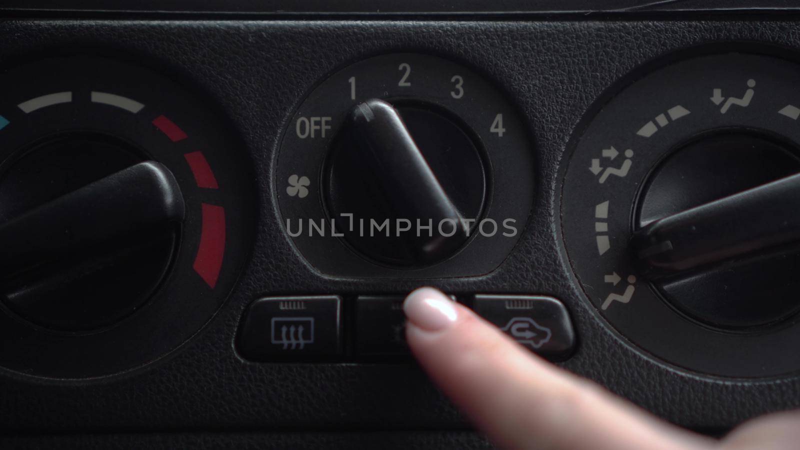 The woman turns on the fan and presses the air conditioner button in the car. Automotive panel close-up. 4k