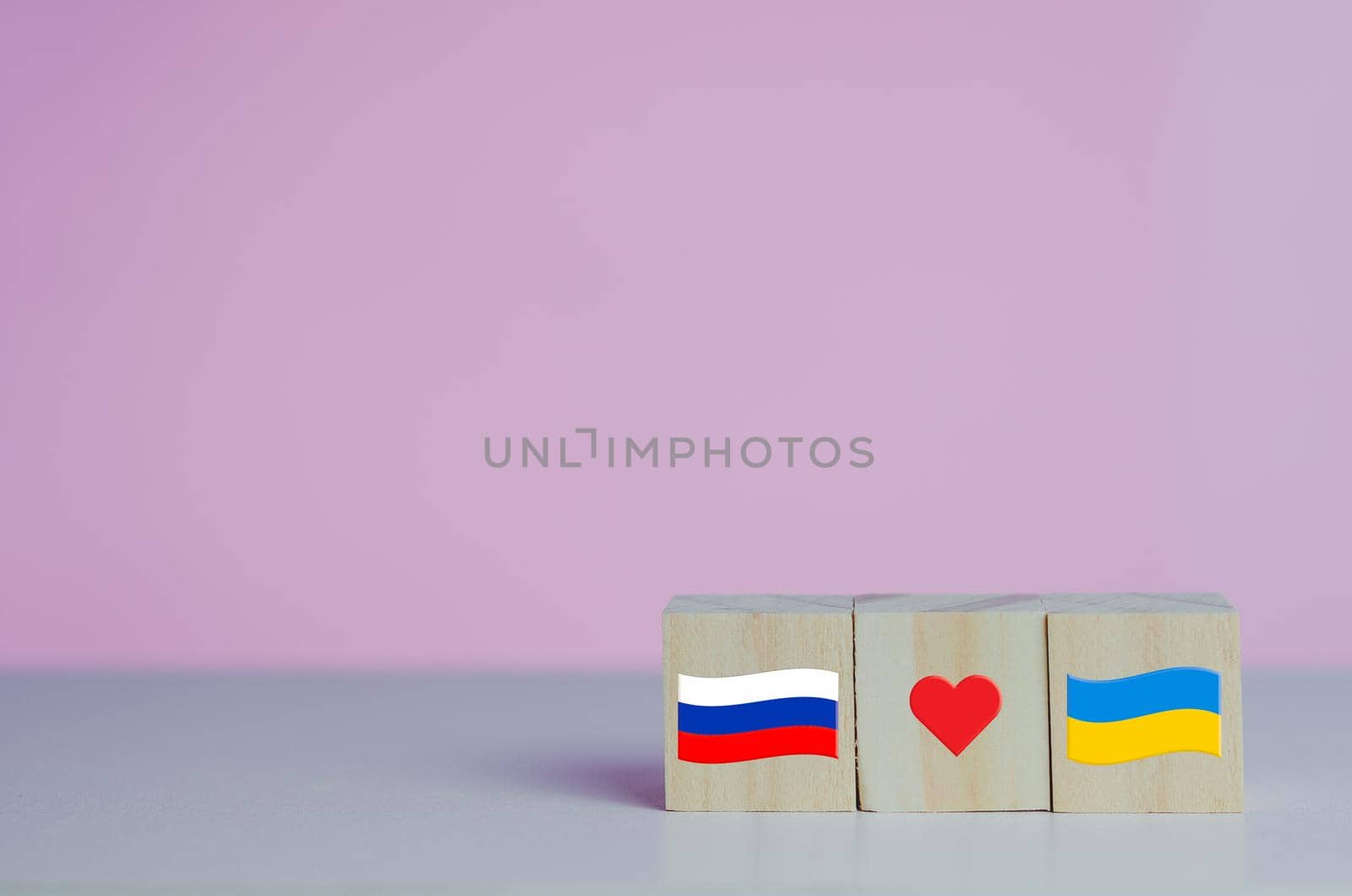 Wooden cubes with russia flag symbol and ukraine flag with red heart icon on background.