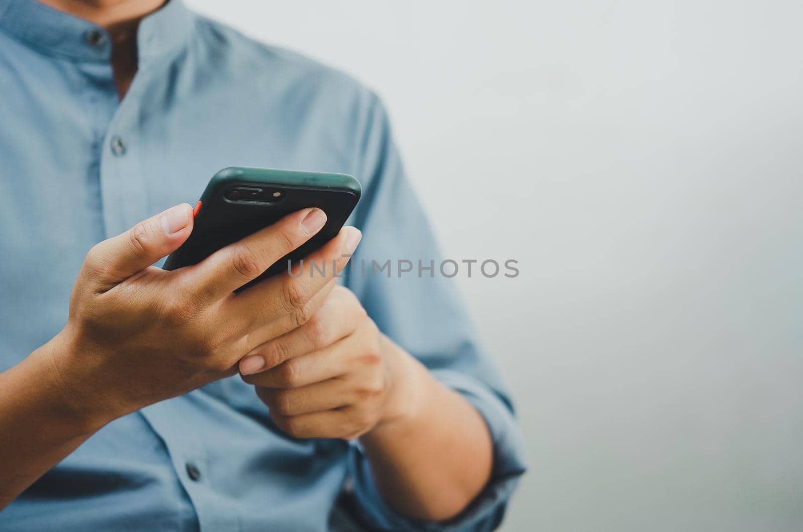 Close up of a man using mobile smart phone searching internet, sending sms, using text messenger or online banking.Copy space.