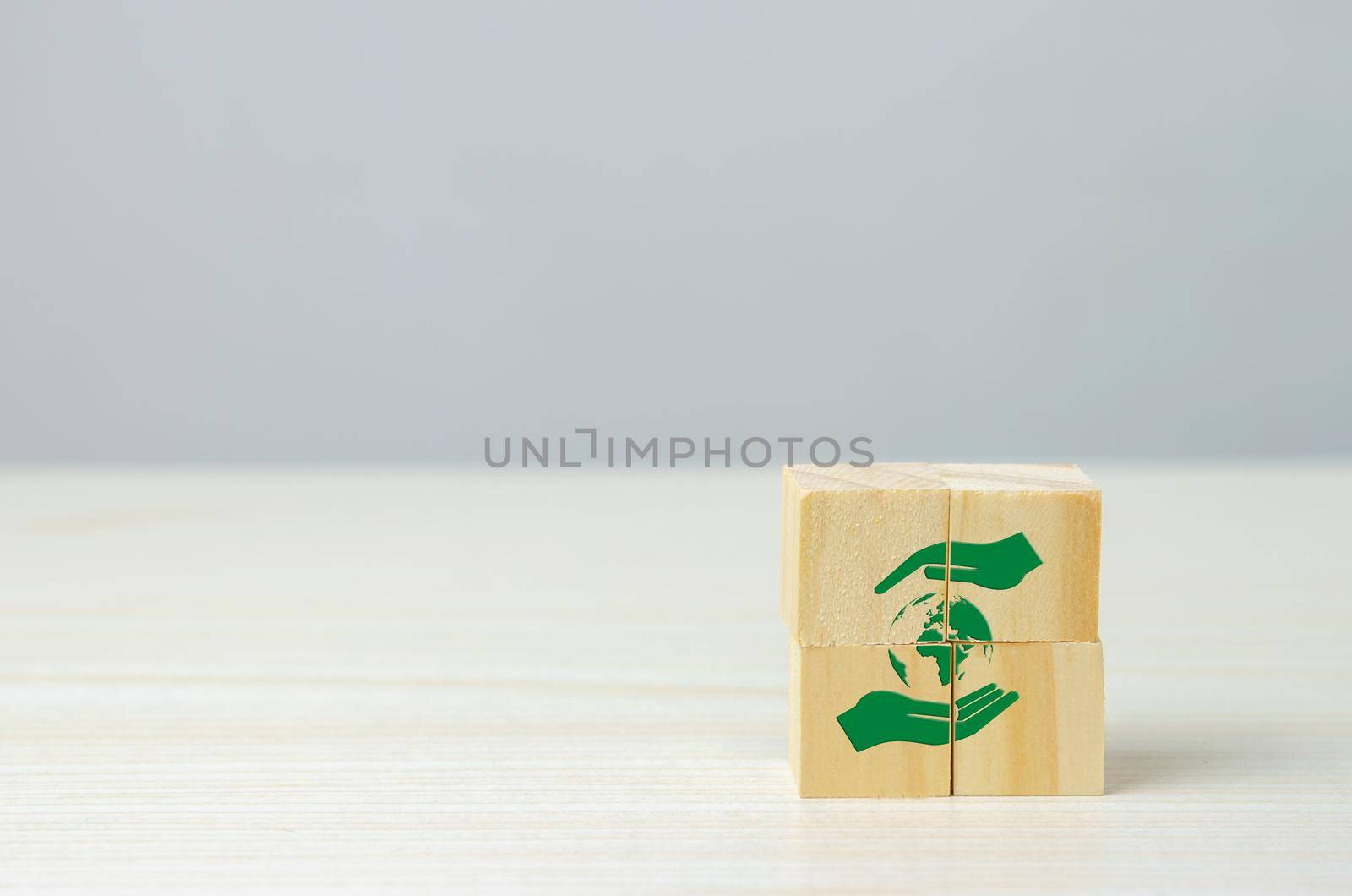 Wooden cube with hand and globe icon net zero. Eco-friendly business and development concept on background.