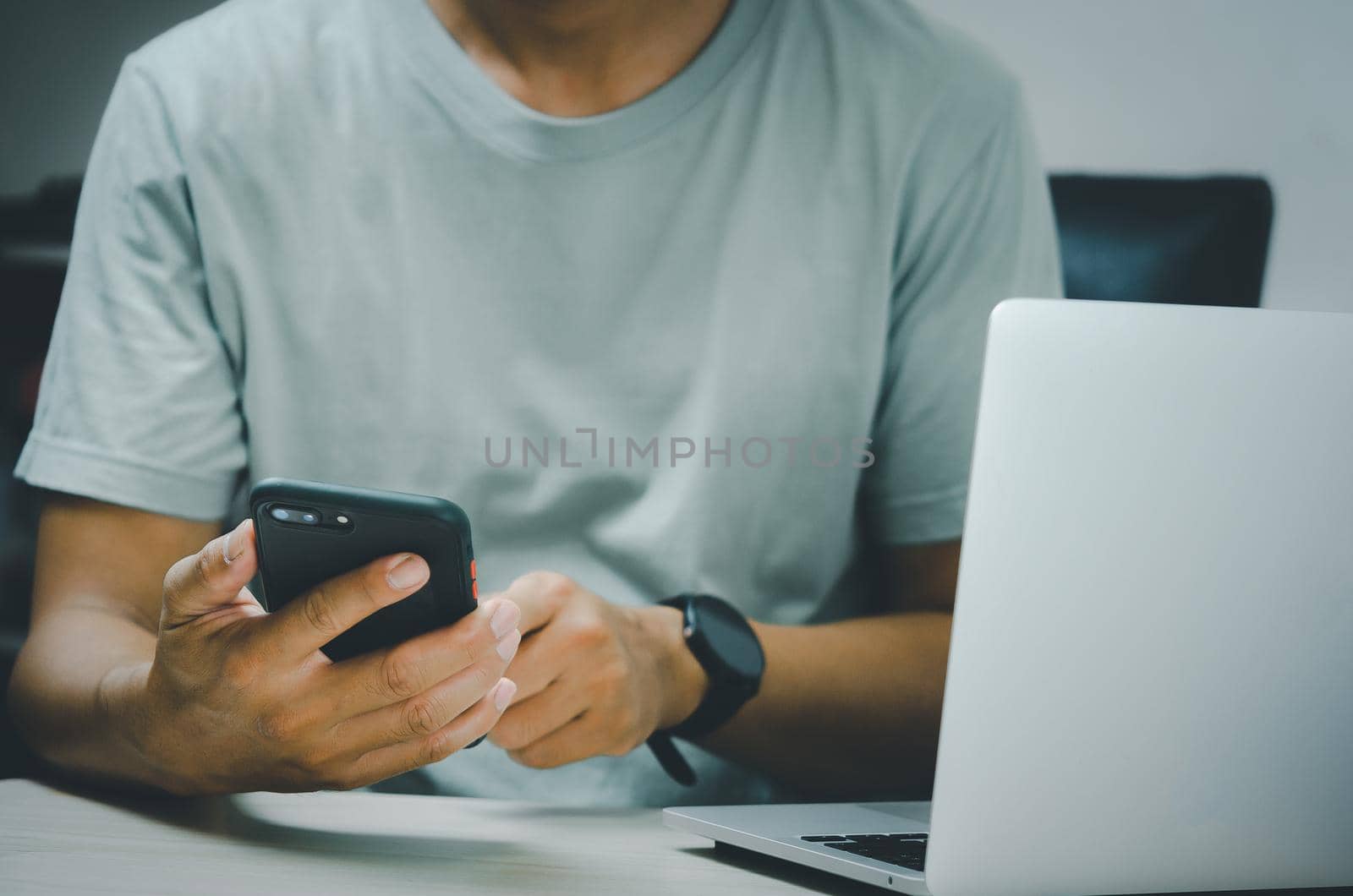 man hand holding smartphone and computer laptop to working technology searching internet, sending sms, using text messenger or online banking.