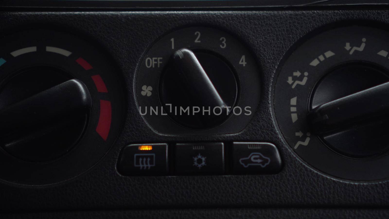 The woman turns on the fan and presses the window heating button in the car. Automotive panel close-up. 4k