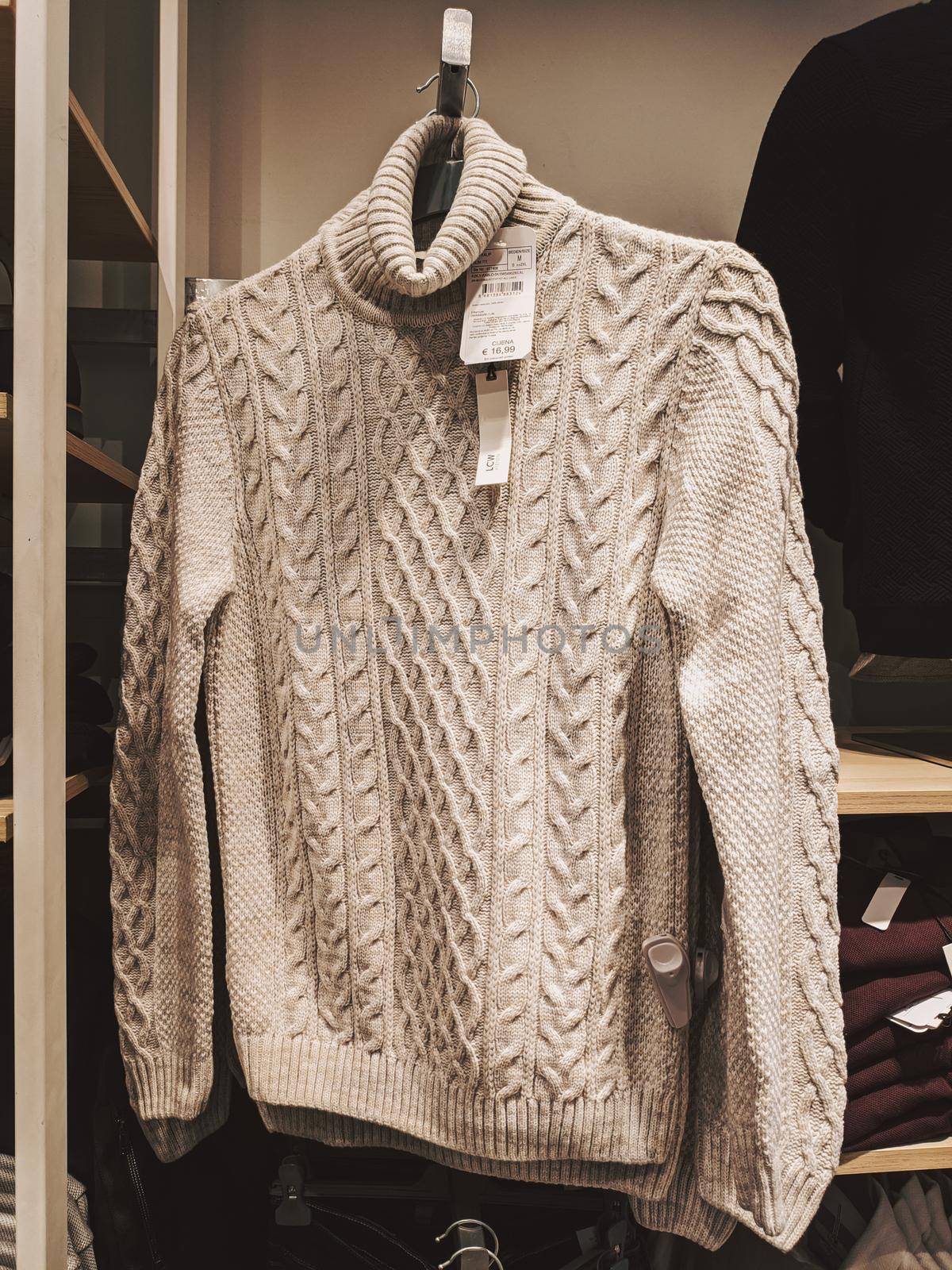 Beige knitted sweater with a neck on a hanger in a store. High quality photo