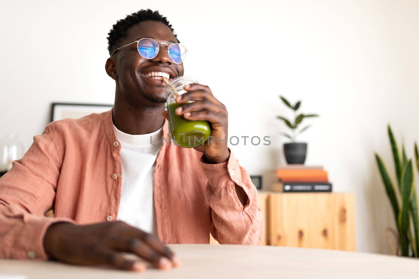 African American black man drinking healthy green juice with bamboo straw looking at camera. Copy space. Wellness and healthy lifestyle concept.