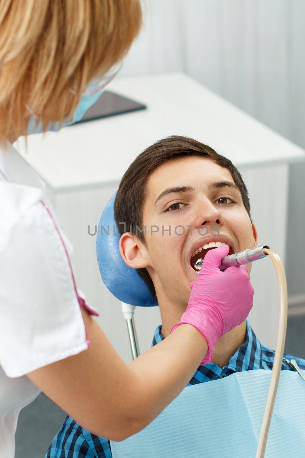 Female dentist treating a patient tooth in dental office with focus on patient mouth. Dentistry