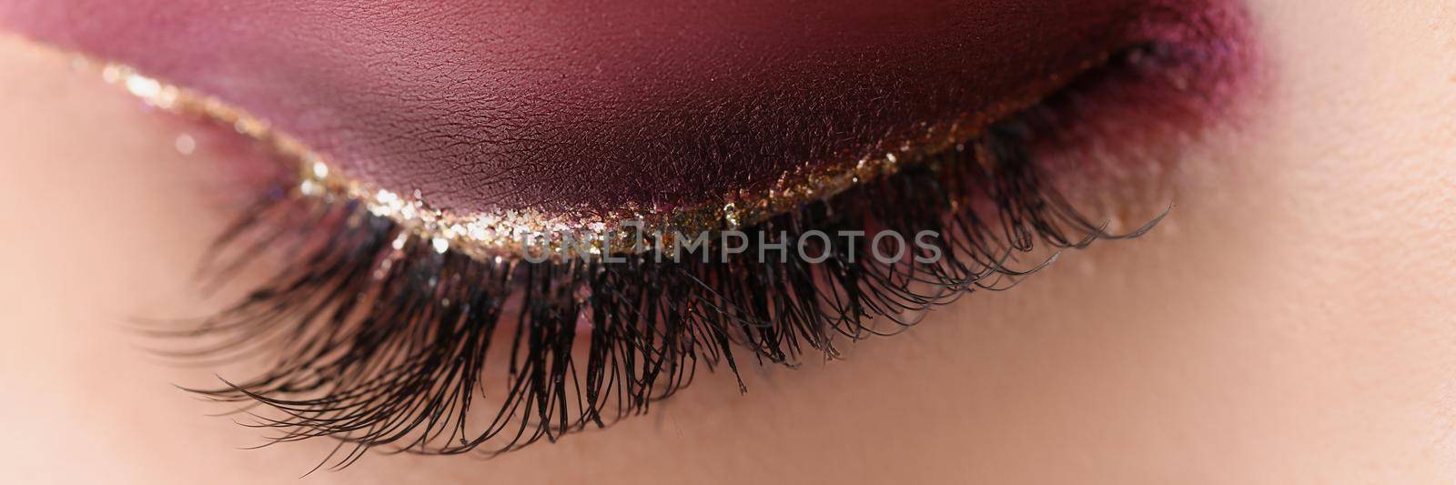 Close-up of pretty makeup on woman face, red autumn colours. Macro shot of bright eye shadow any festive celebration. Mua, beauty, makeup, artist concept