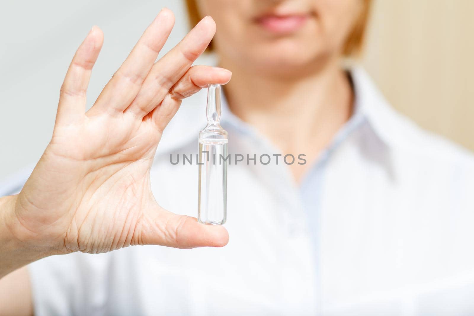 Hand of female doctor with ampoule and medicine. Selective focus on ampoule