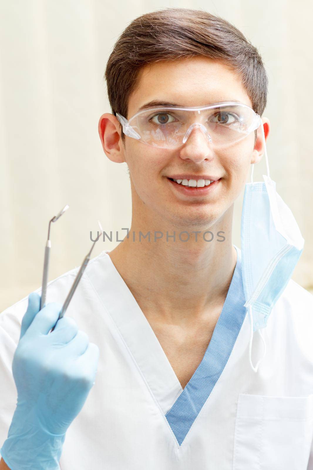 Portrait of handsome male dentist with dental tools in the dental clinic by mvg6894