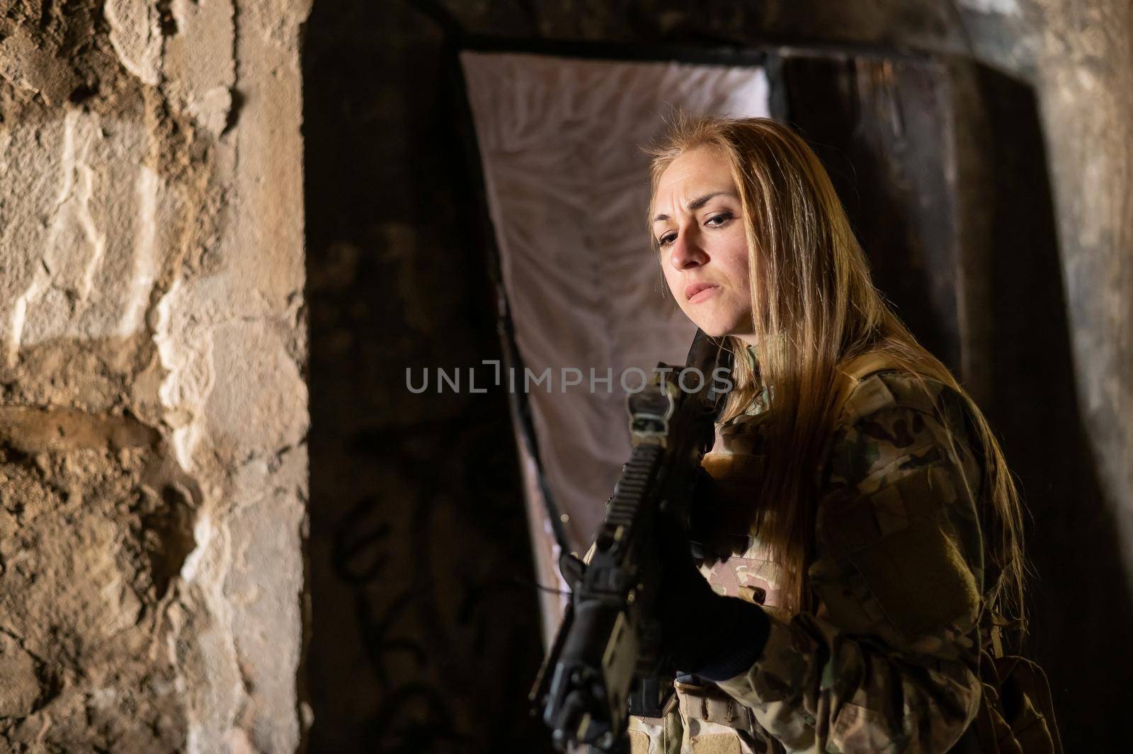 Caucasian woman in army uniform holding a machine gun and standing near an open coffin