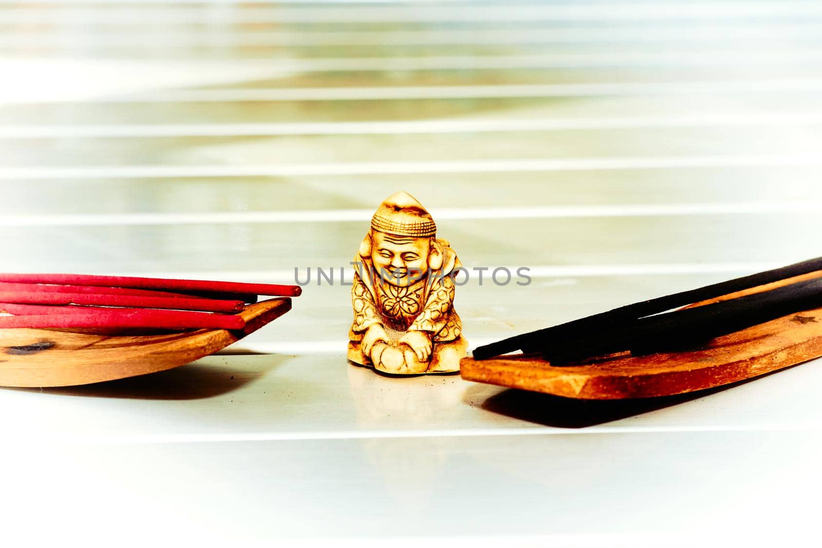 Gold buddha figurine and an incense on white table by jovani68