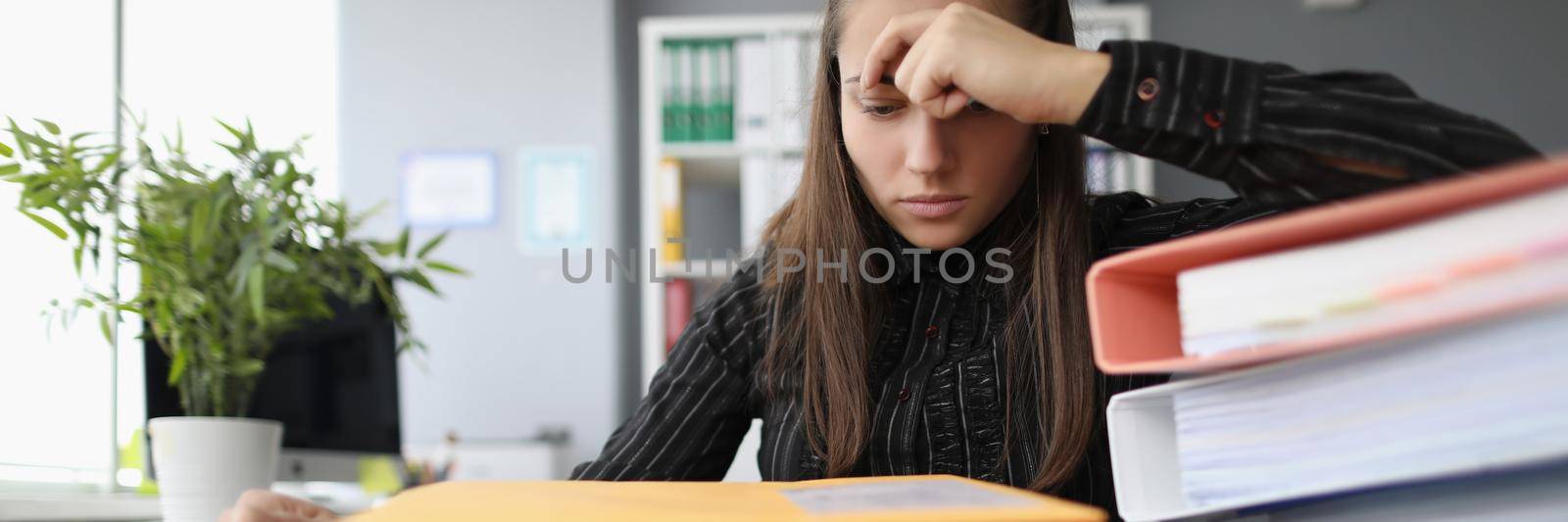 Portrait of tired overworked woman with hopeless look on docs pile. Stressful and exhausted clerk in office, stack with papers on desk. Hardworker concept