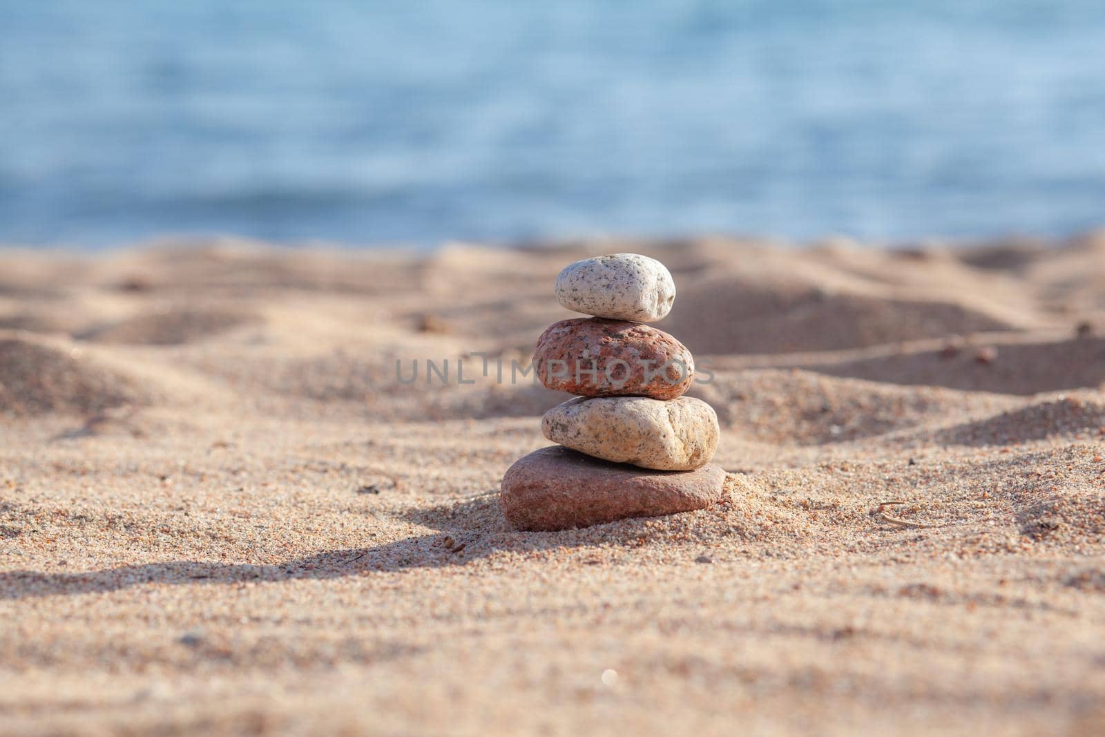 Round stones lie on top of each other in a column on the seashore by AnatoliiFoto