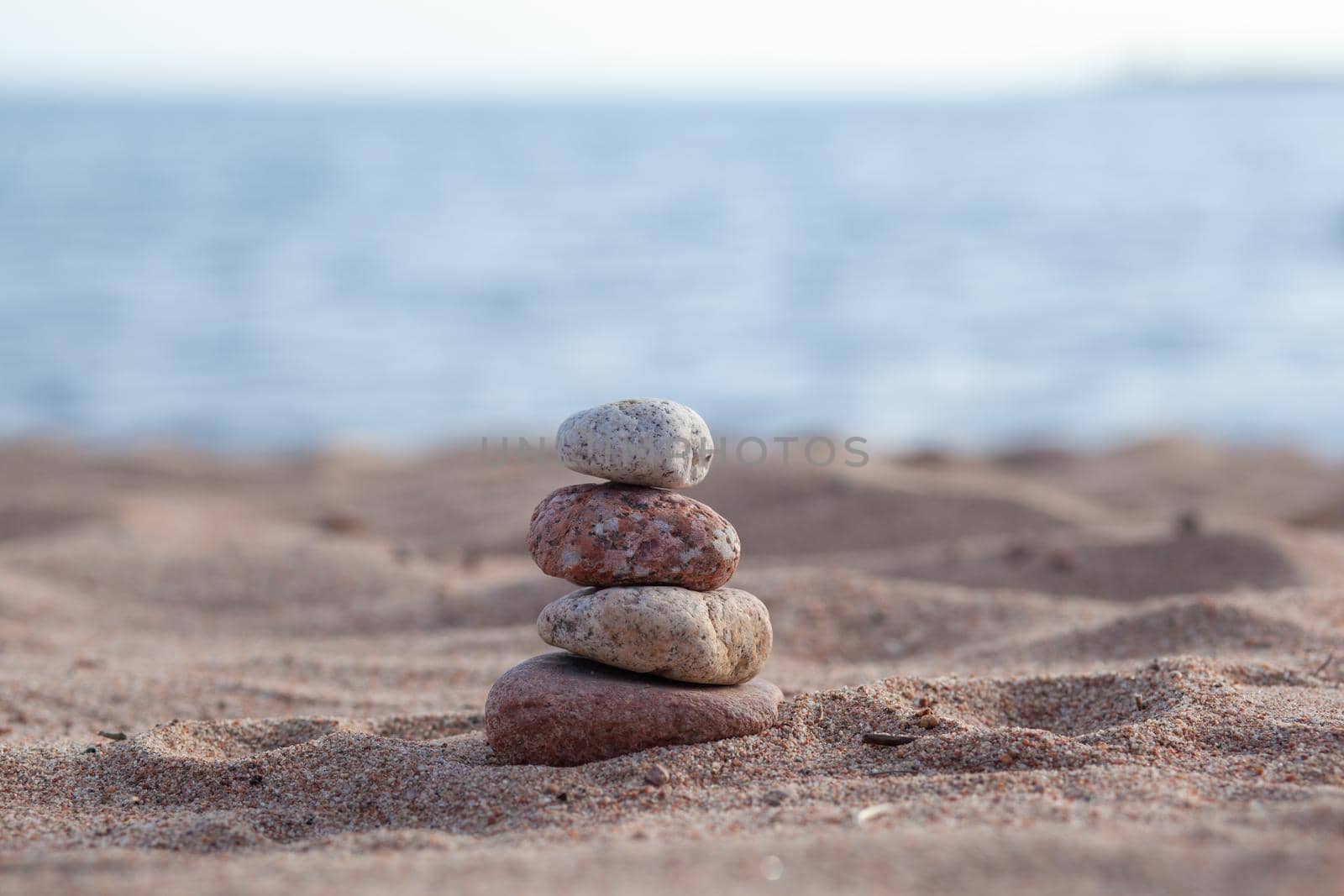 Round stones lie on top of each other in a column on the seashore on a sunny summer day. The concept of order and tranquility