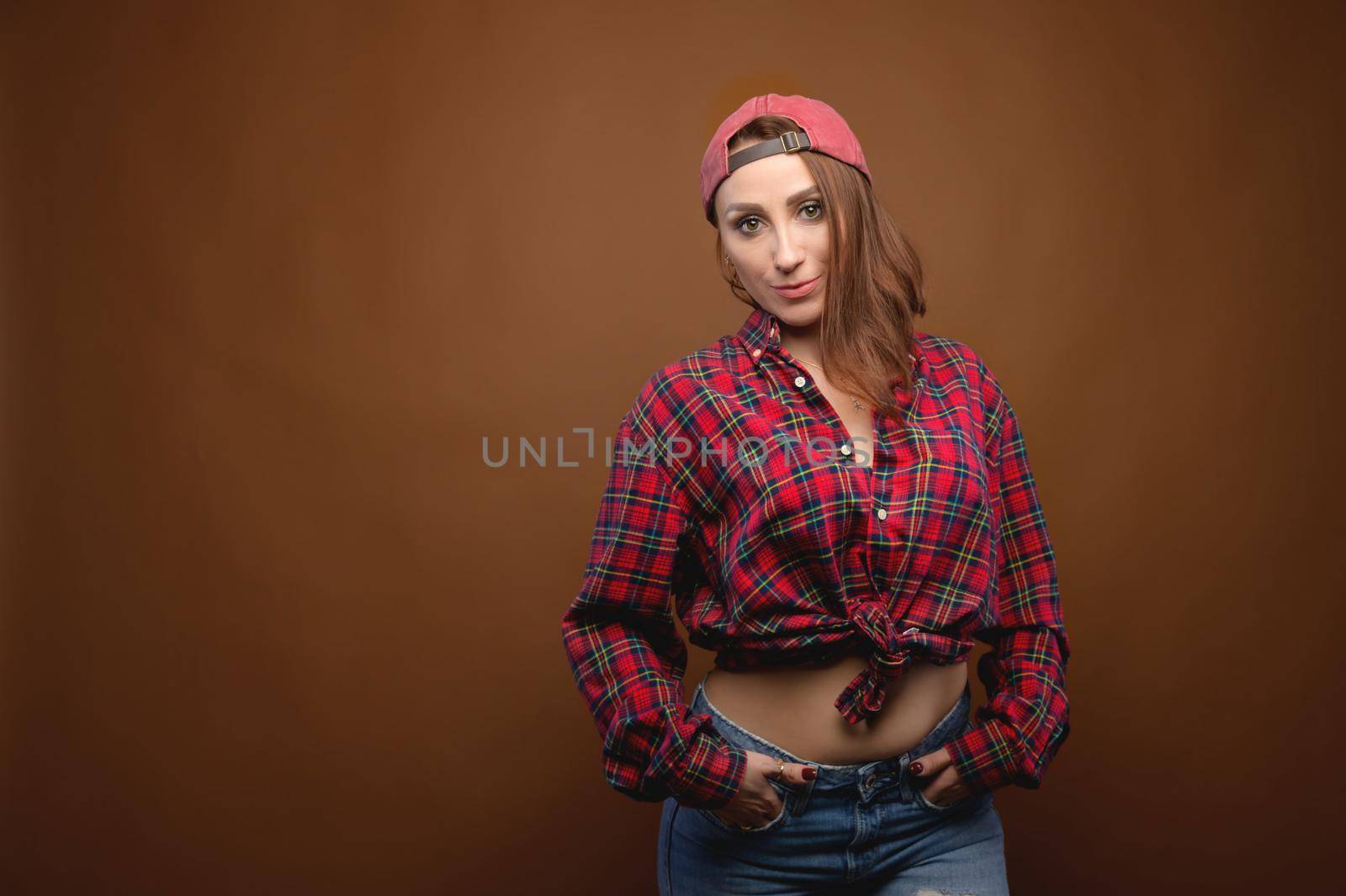 Sexy young caucasian woman in a plaid shirt on a brown background. Studio photography.