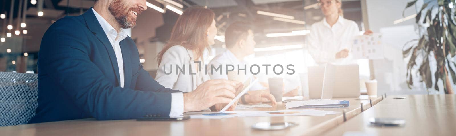 Creative smiling businessman working on a tablet during a meeting with a team. High quality photo