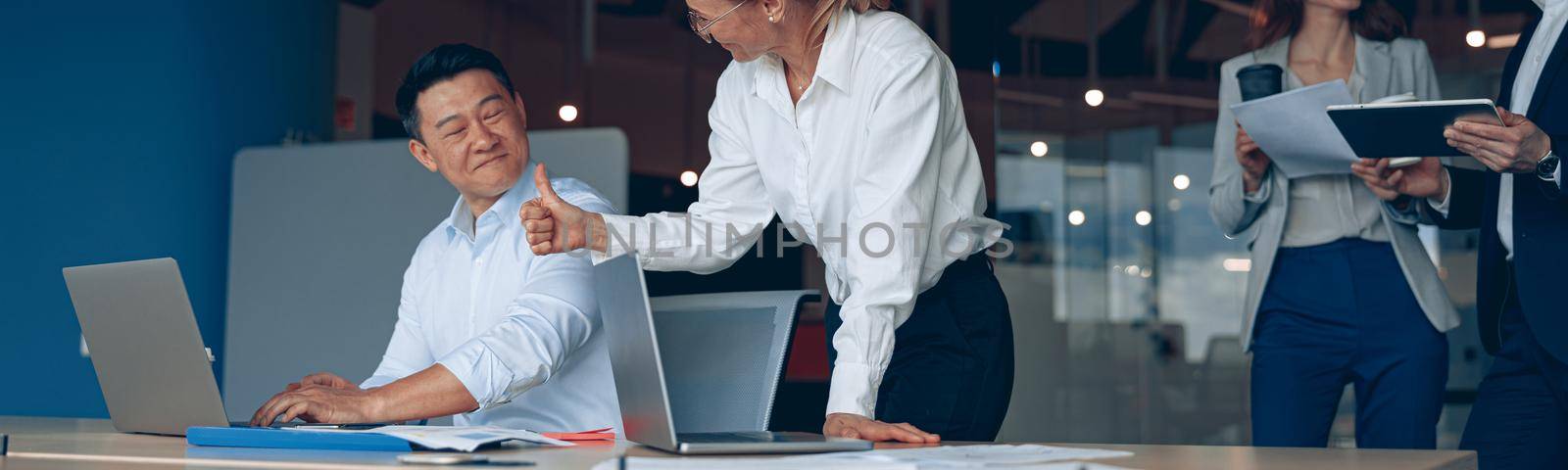 mature female employee discussing online project, showing presentation to skilled team leader.