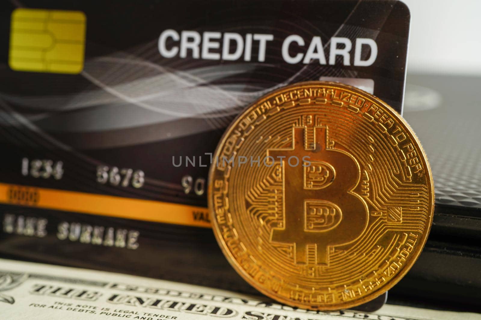 Bangkok, Thailand - December 15, 2021 Golden bitcoin with credit card on US dollar banknotes money for business and commercial, Digital currency, Virtual cryptocurrency.