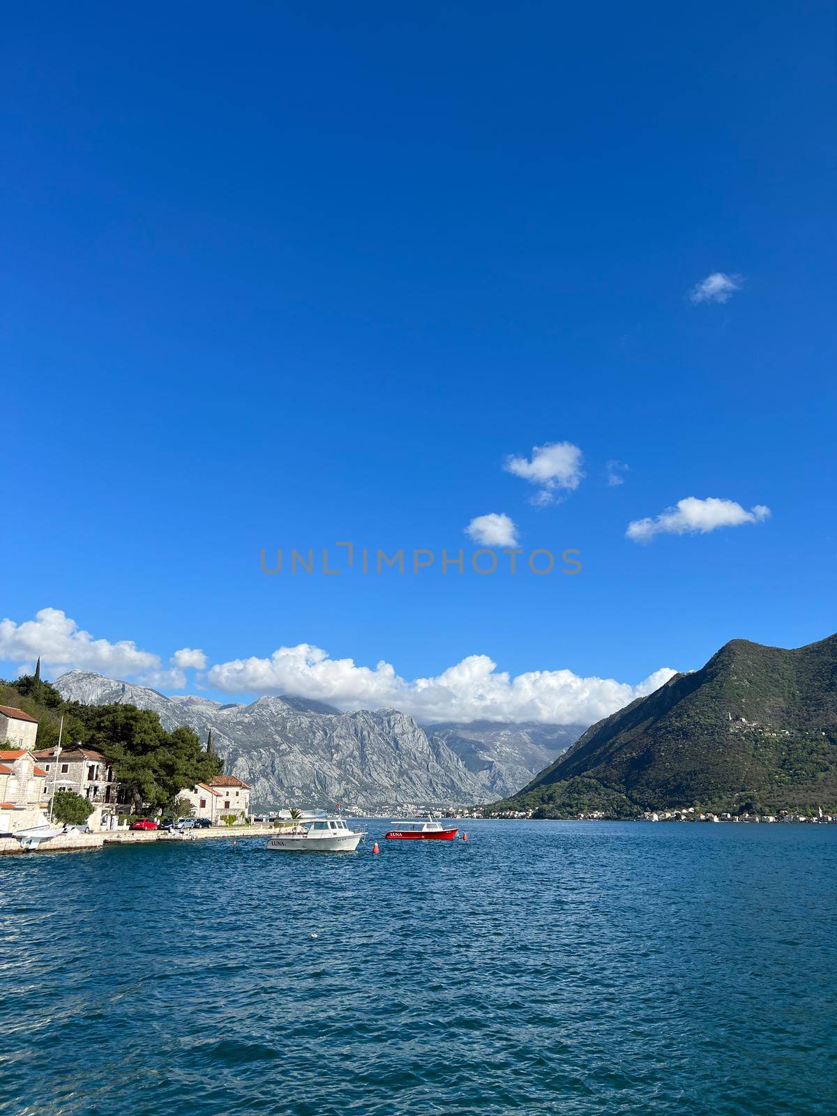 Boats sail along the Kotor Bay past the coast of Perast. Montenegro. High quality photo