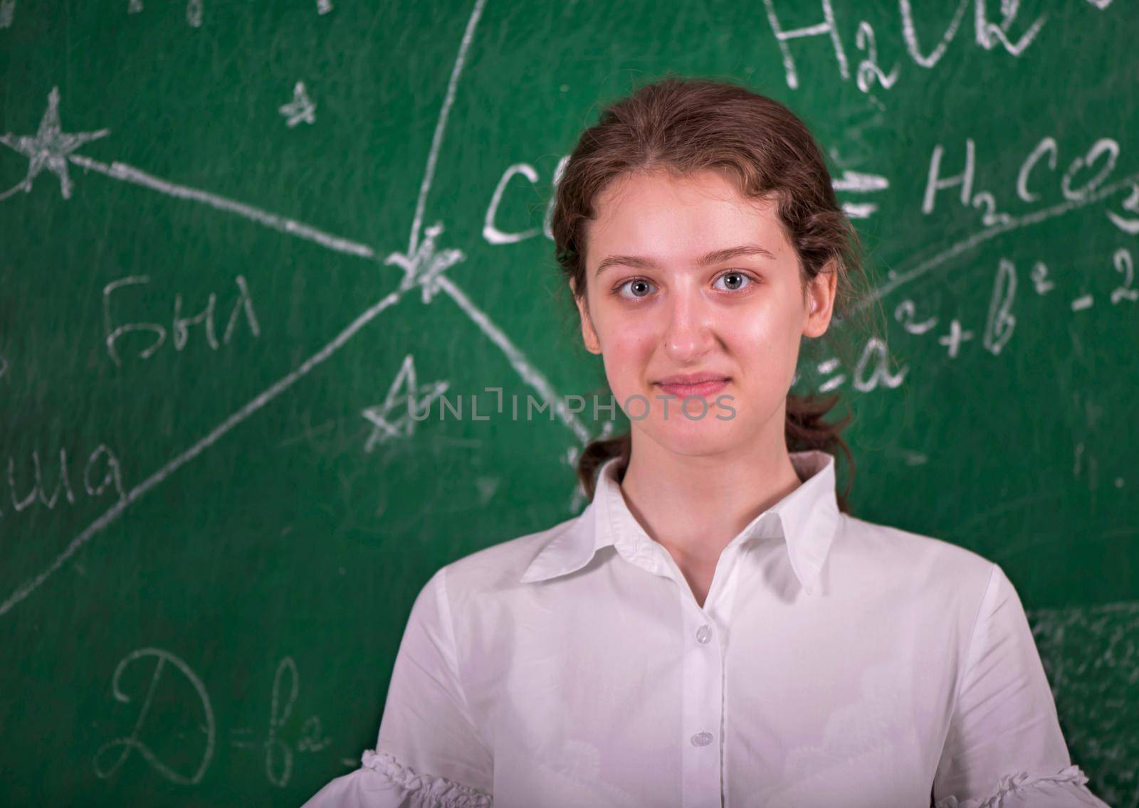 Student girl standing near clean blackboard in the classroom by aprilphoto