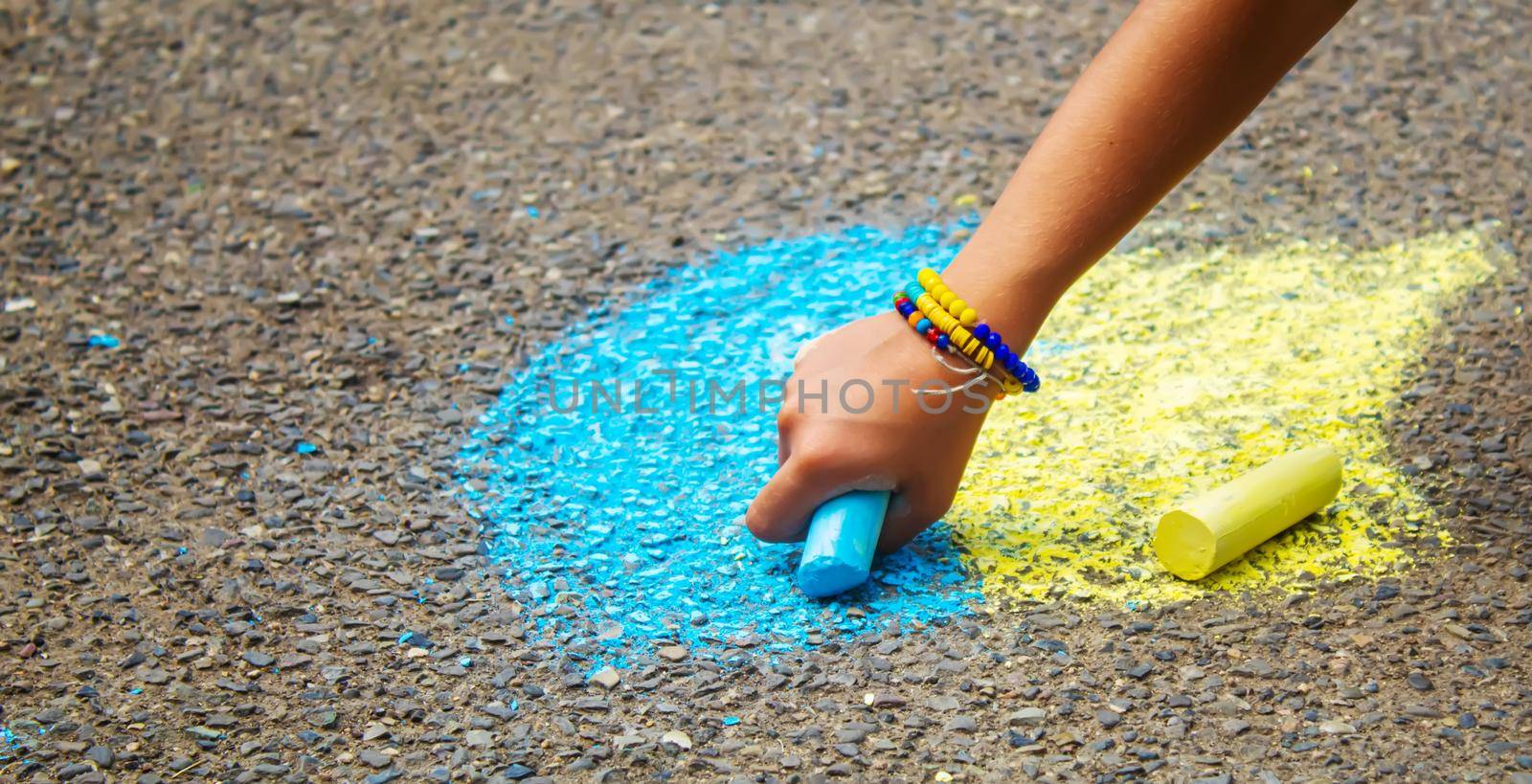 Children draw the Ukrainian flag house on the pavement. Selective focus. by mila1784