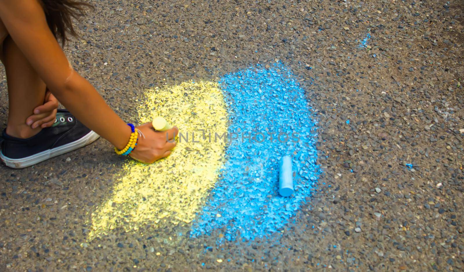 Children draw the Ukrainian flag house on the pavement. Selective focus. by mila1784