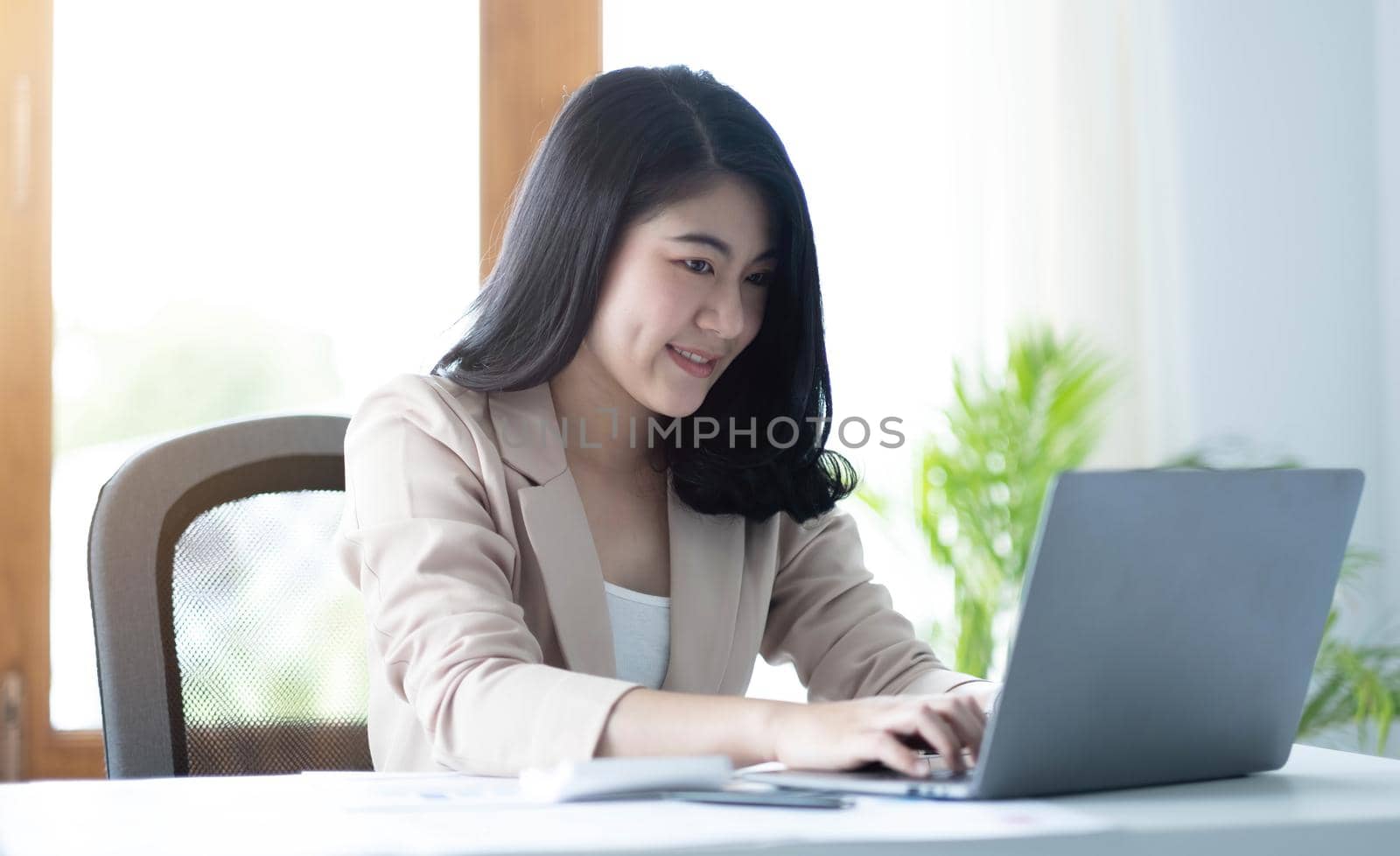 Beautiful young asian woman sitting at coffee shop using laptop. Happy young businesswoman sitting at table in cafe with tab top computer. by wichayada