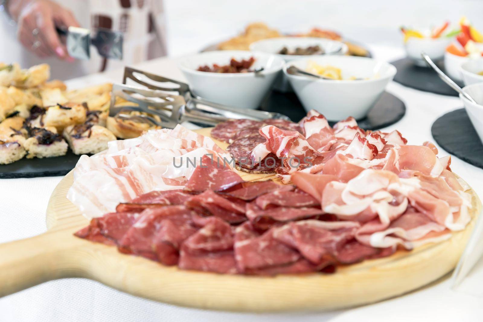 Wood cutting board with prosciutto, bacon, salami and bresaola. Meat platter.