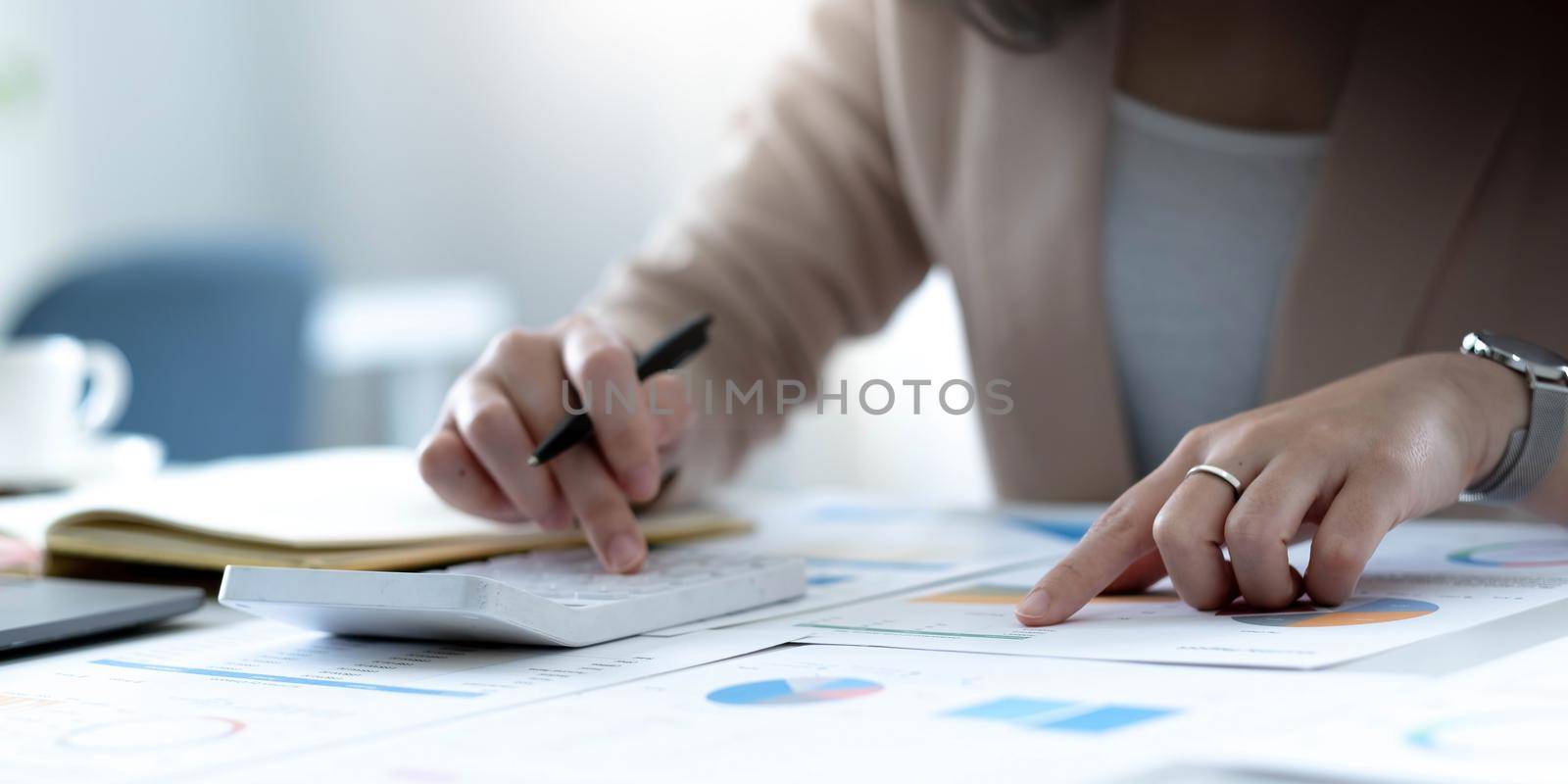 Businesswoman accountant working audit and calculating expense financial data on graph documents, doing finance in workplace..