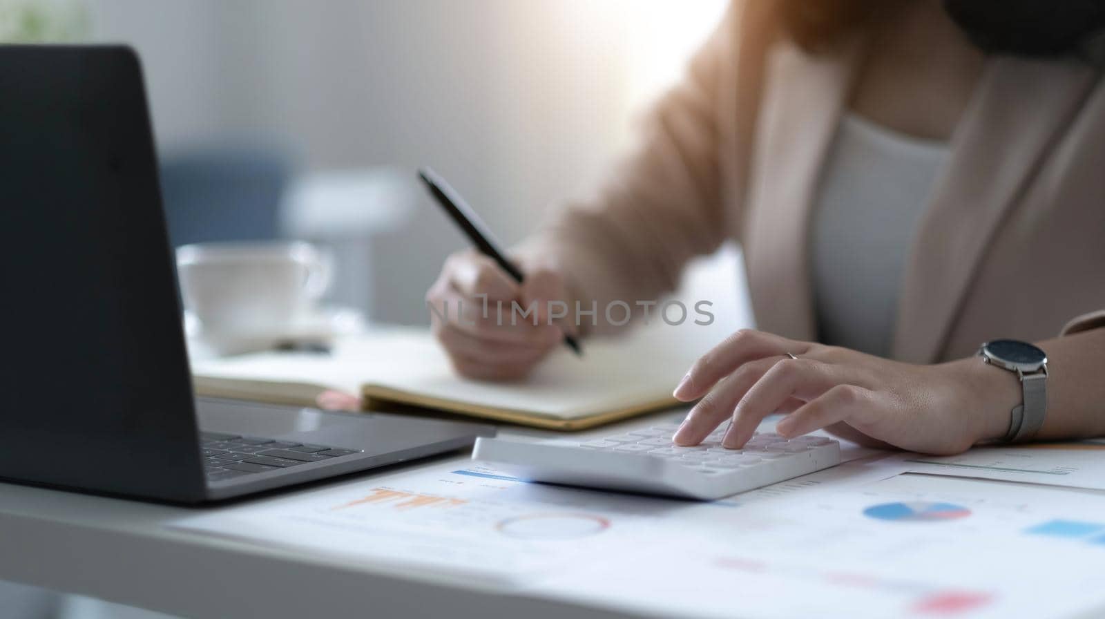 Close up Business woman using calculator and laptop for do math finance on wooden desk in office and business working background, tax, accounting, statistics and analytic research concept.