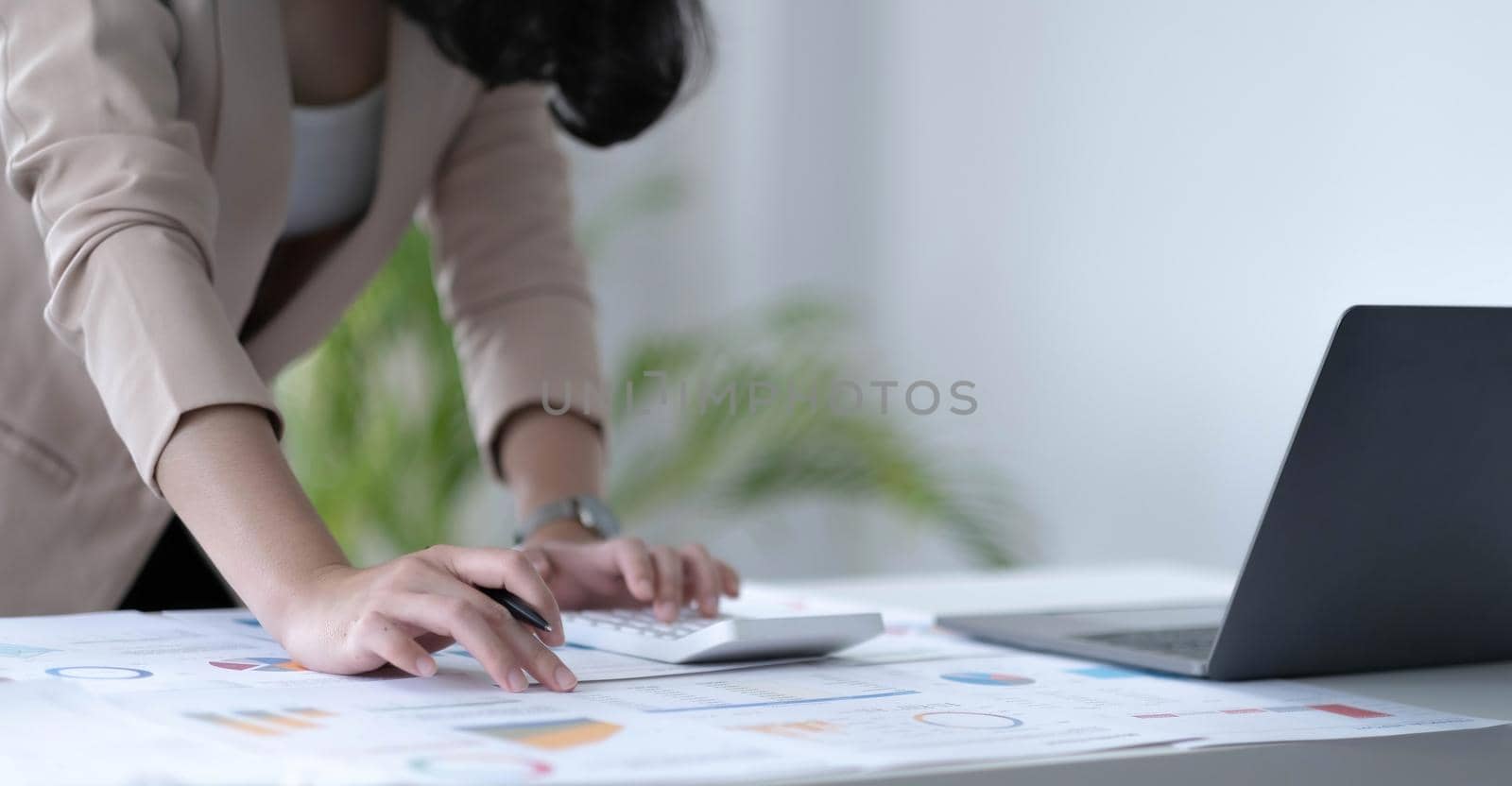 Close up Business woman using calculator and laptop for do math finance on wooden desk in office and business working background, tax, accounting, statistics and analytic research concept.