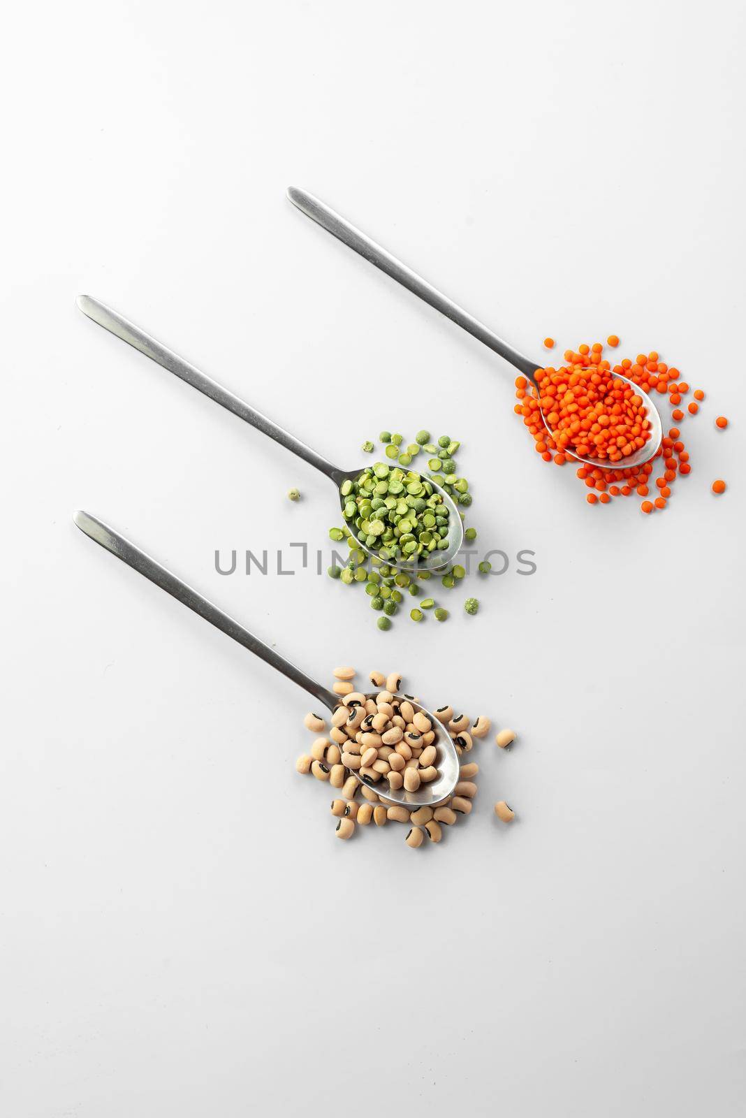 3 spoons on white background with Ancient grain food. Useful food for those who are on a diet and watching their health. red Lentils and green peas on white beans black eyes