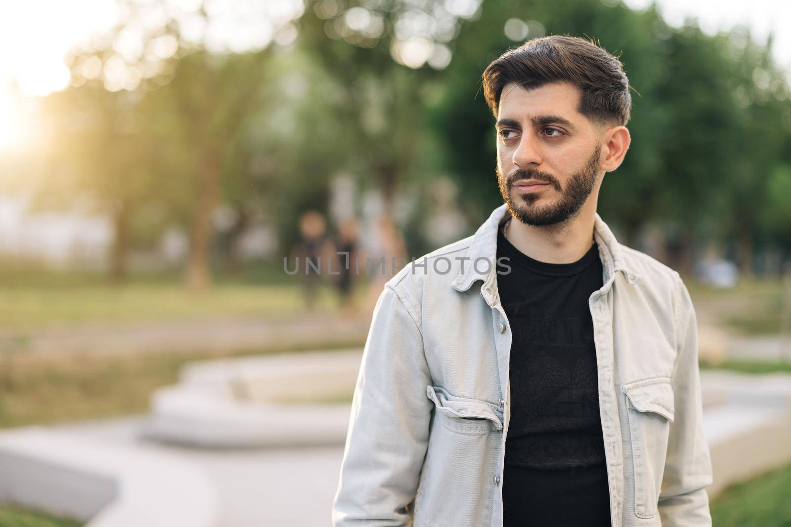 Gorgeous face of young bearded mixed-race elegant man with brown eyes. Caucasian european man looking stright outdoors. Stand outdoor relax. Happy relax. Male portraits. by uflypro