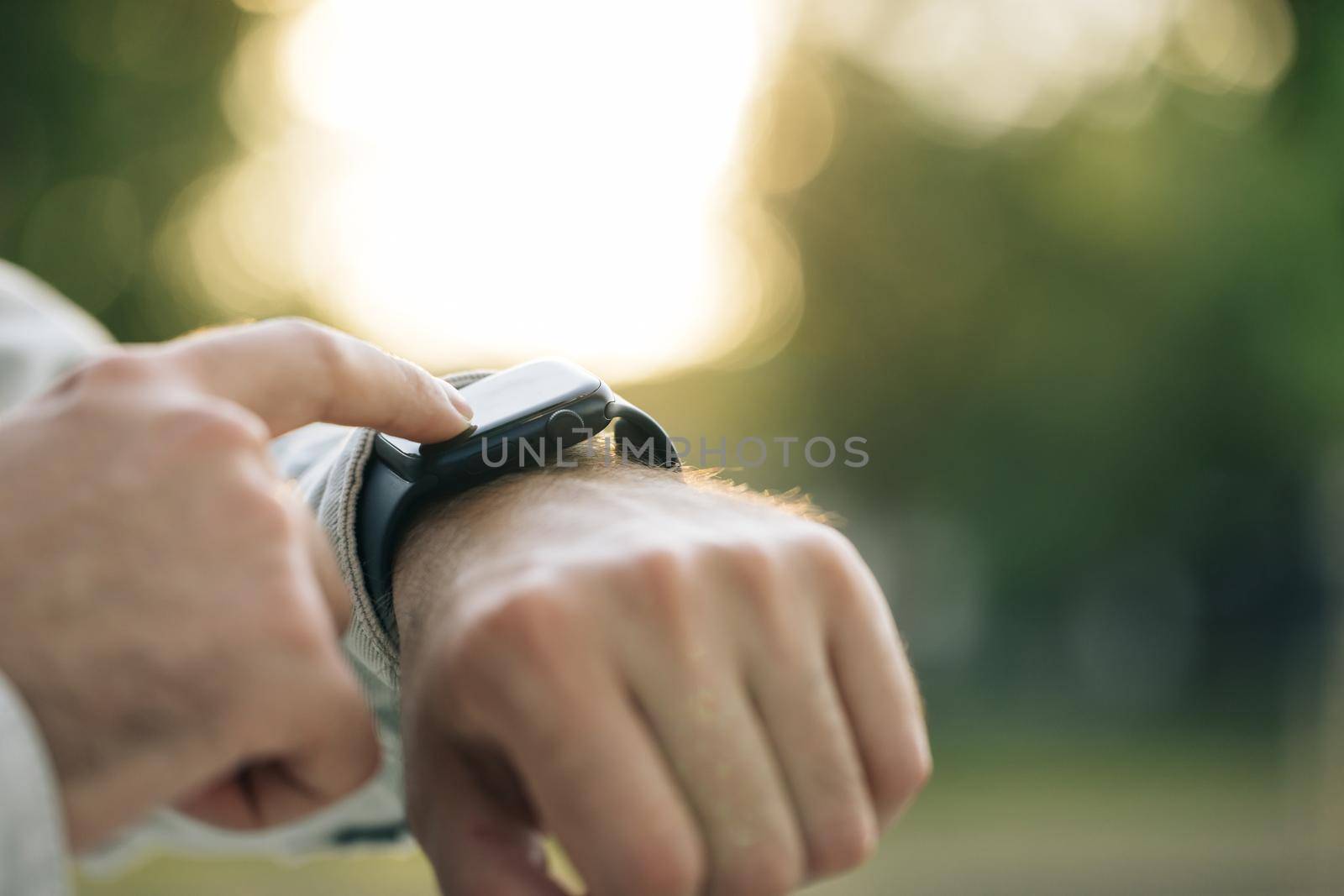Smart watch. Smart watch on a man's hand outdoor. Man's hand touching a smartwatch. Close up shot of male's hand uses of wearable smart watch at outdoor in sunset.