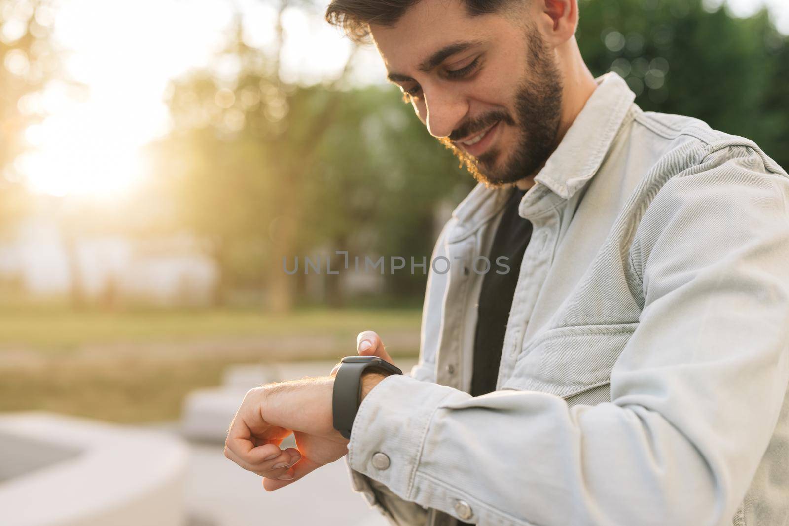 Smartwatch on a man's hand outdoor. Man's hand touching a smart watch. Closeup shot of male's hand uses of wearable smart watch at outdoor. Smartwatch by uflypro