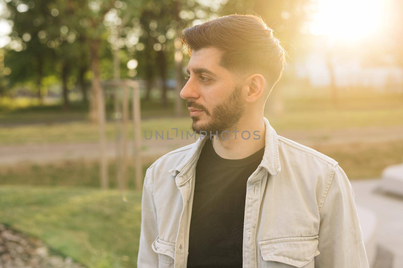 Caucasian european man looking stright outdoors. Stand outdoor relax. Gorgeous face of young bearded mixed-race elegant man with brown eyes. Male portraits