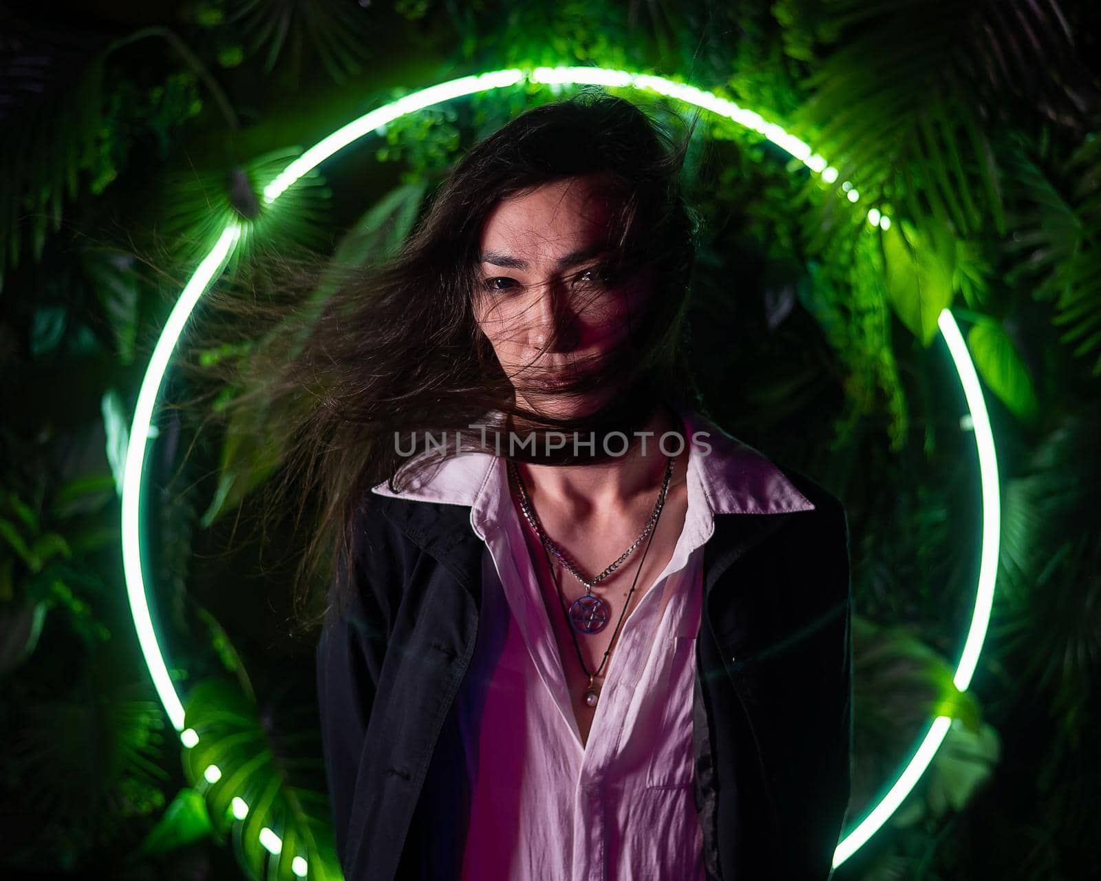 Portrait of an Asian man against the background of a circular lamp in the studio with neon light