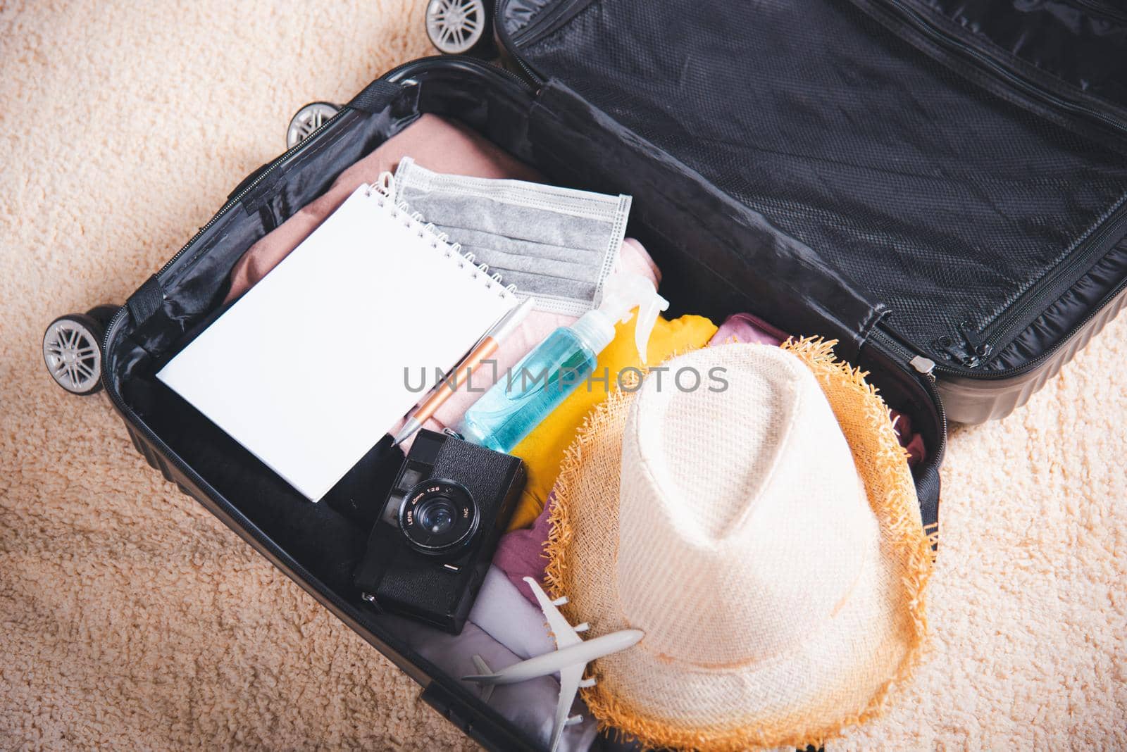 Open suitcase with traveler belongings clothes and accessories of things ready packing to be taken on summer holiday, Travel vacation luggage preparations concept, top view