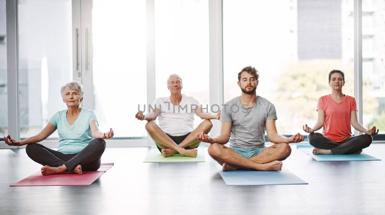 Perfectly balanced. Full length shot of a group of people meditating while practicing yoga. by YuriArcurs
