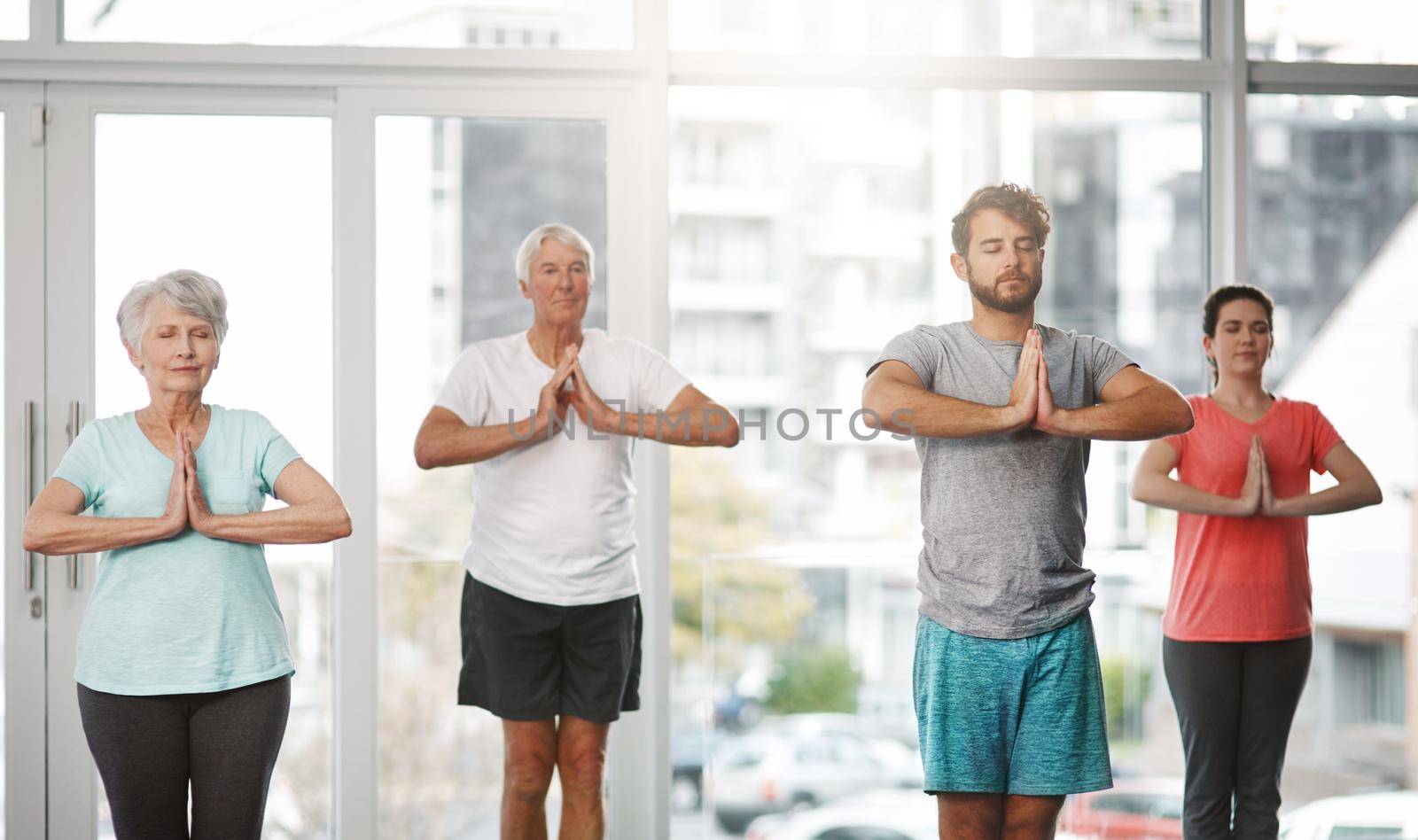 Finding their center. a group of people meditating while practicing yoga. by YuriArcurs