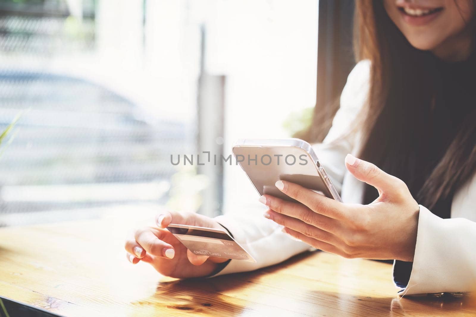 Asian young woman using a mobile phone and credit card for online shopping.