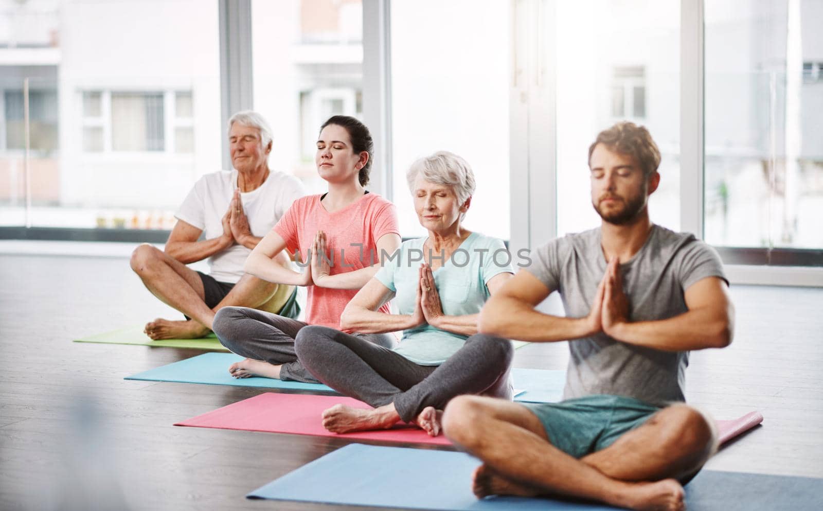 Full length shot of a group of people meditating while practicing yoga.