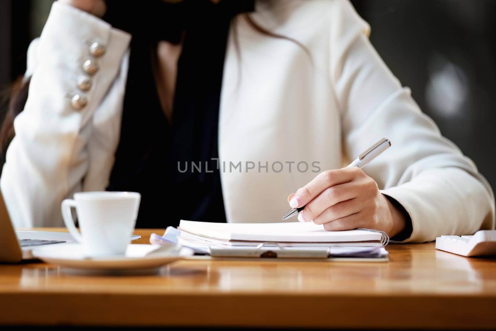 Asian businesswoman taking business notes while talking on the phone by Manastrong