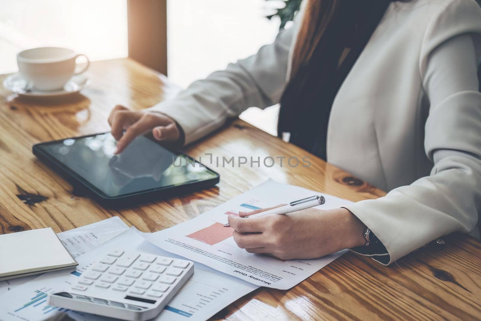 business woman using pen pointing budget document with tablet computer for data analysis, marketing, accounting by Manastrong